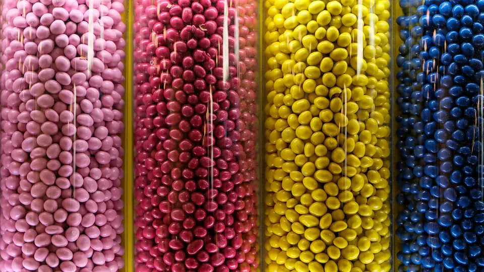 Glazen potjes vol suikerparels in roze, geel en blauw